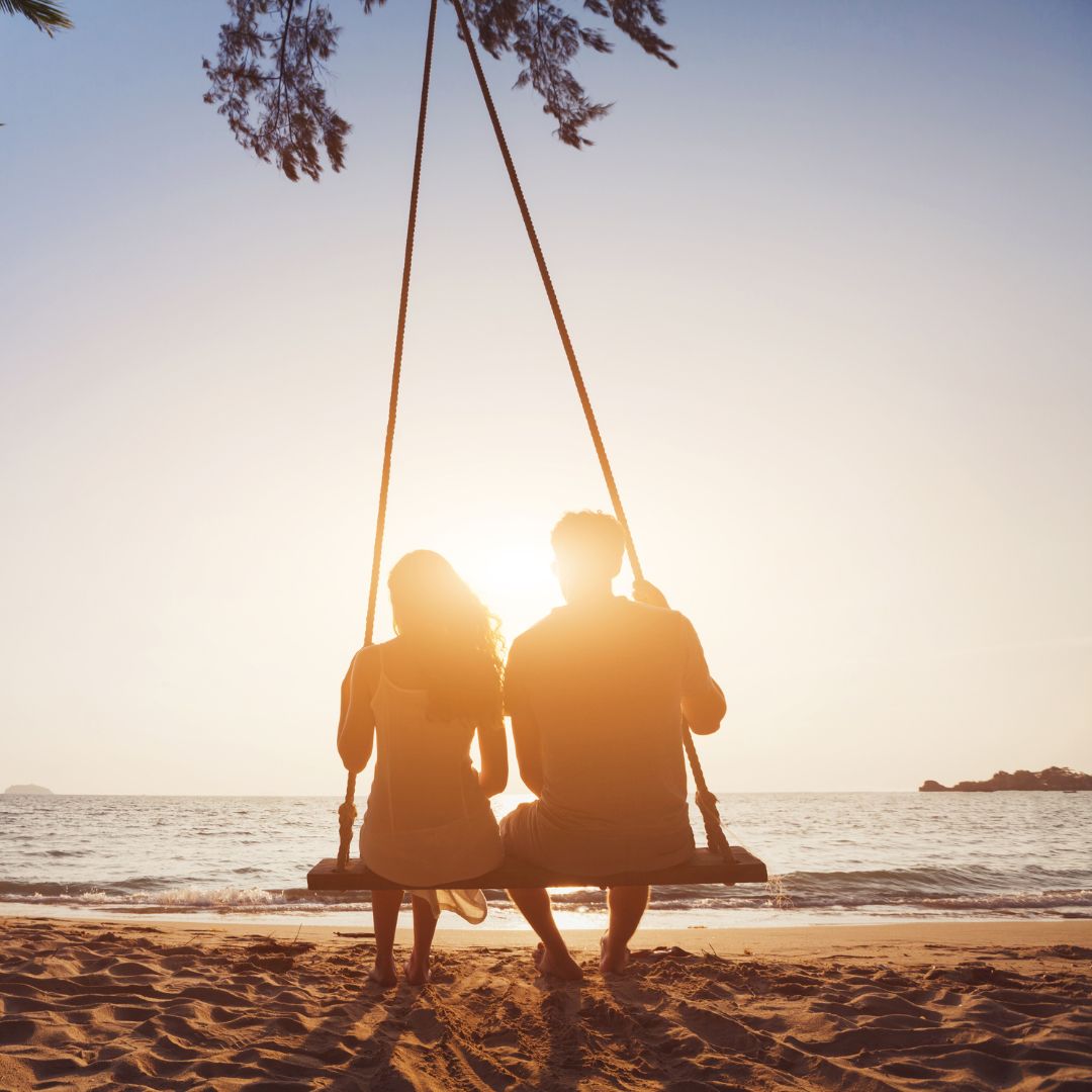 a couple swinging on a beachfront swing