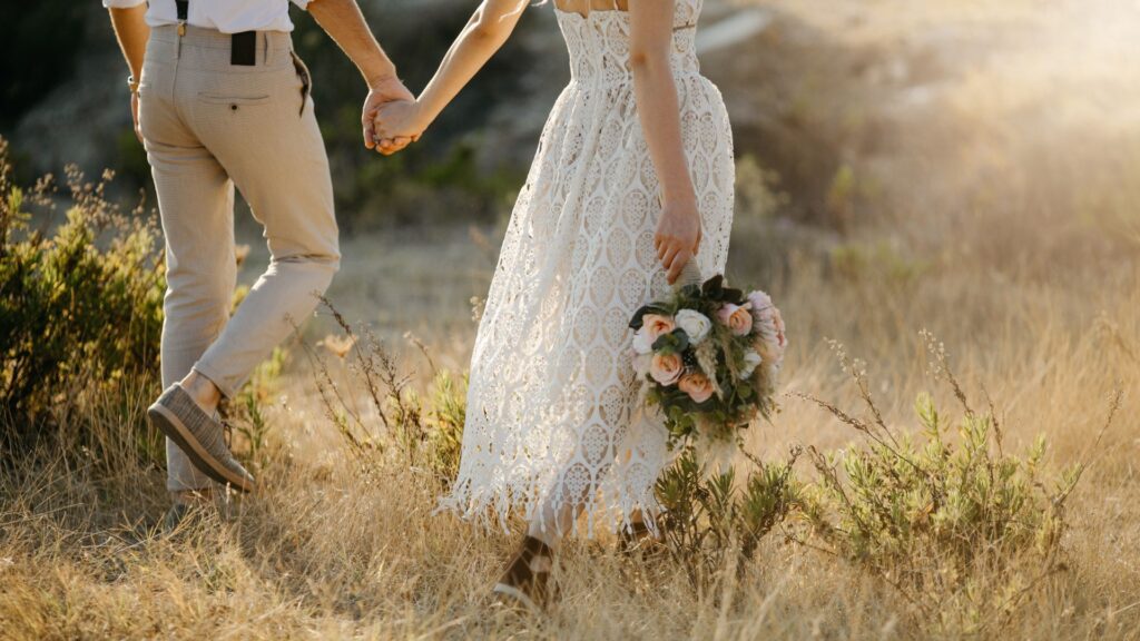 bride and groom walking in grass